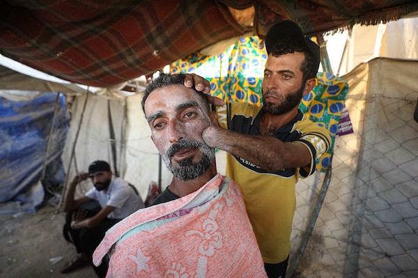 لاجئ فلسطيني يتحدى فقدان يده ويواصل مهنة الحلاقة في مخيم النصيرات